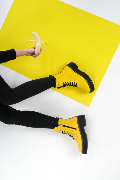piernas de una niña en botas de cuero amarillo sobre un fondo claro y brillante. moda fotografía moda lookbook nueva colección de zapatos otoño invierno - Foto, Imagen