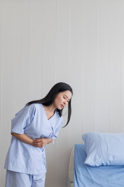 A young patient with stomachache standing beside the hospital bed - Photo, image