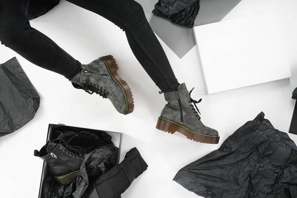                    mujer en zapatos de cuero negro de la nueva colección en un fondo blanco piernas de niña en zapatos de moda hechos de cuero ecológico otoño-invierno 2020. caja de zapatos y bolso sobre un fondo blanco             - Foto, Imagen