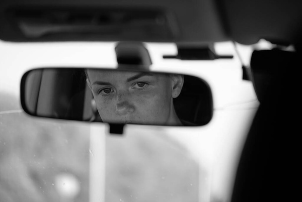 Reflection of young female face and eyes in rearview mirror of a car. Woman driver. - Φωτογραφία, εικόνα