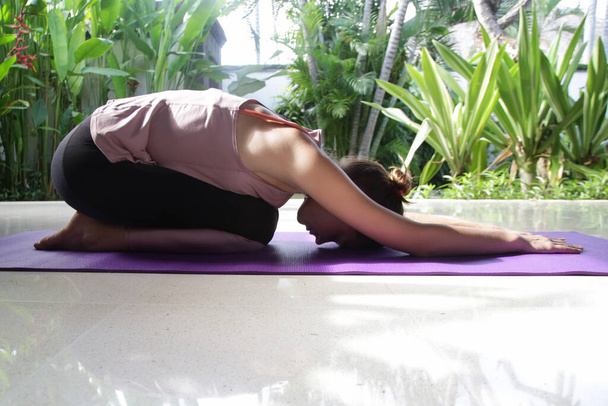 Jonge vrouw die thuis yoga oefeningen doet. Gezond levensstijl concept. - Foto, afbeelding