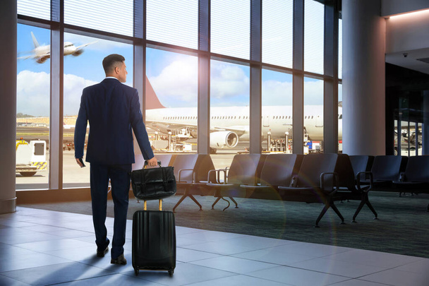 Επιχειρηματίας με τσάντα και ταξιδιωτική βαλίτσα στο τερματικό σταθμό του αεροδρομίου. Καλοκαιρινές διακοπές - Φωτογραφία, εικόνα