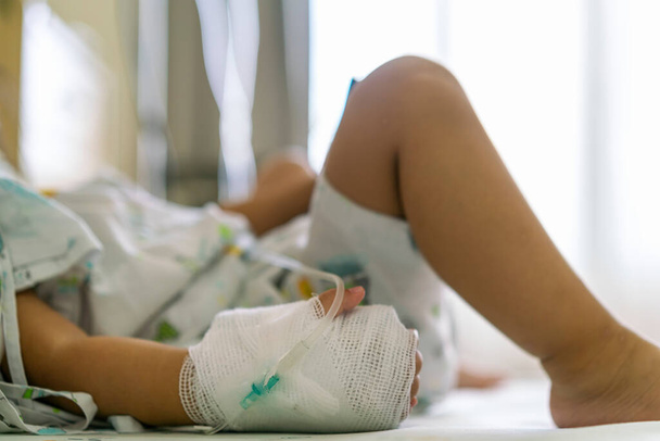子供や女の子の患者は、ベッドの上に残り、手はまだ生理食塩水やビタミンや輸液静脈注射のための機器の医療とロック - 写真・画像