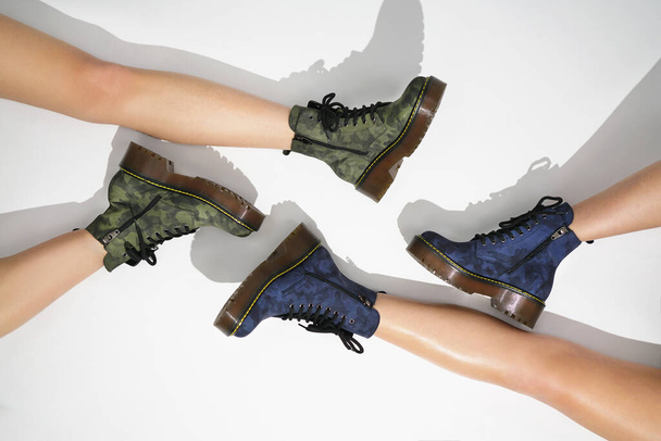 νέα συλλογή μόδας υποδημάτων φθινόπωρο χειμώνα 20 / 21 στα πόδια των μοντέλων μπότες στο ύφος ενός στρατιωτικού σε έγχρωμο φόντο φωτογραφίες μόδας των παπουτσιών - Φωτογραφία, εικόνα