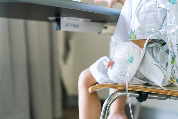 Child or girl patient sit on chair and hand still lock with equipment medical for injection for saline or vitamin or infusion intravenous - 写真・画像