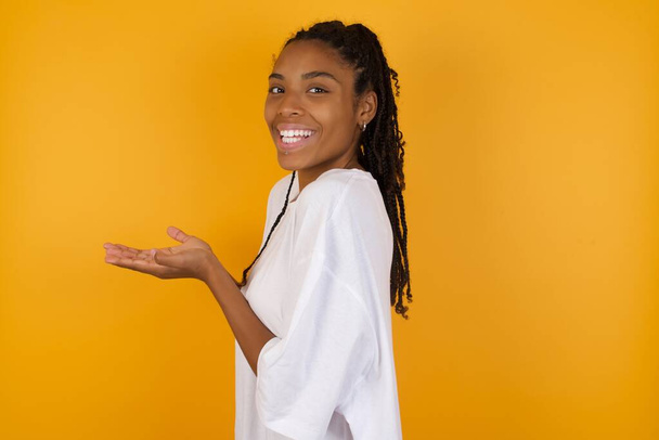 смеющаяся африканская американка на жёлтом фоне и попрошайничающая руками  - Фото, изображение