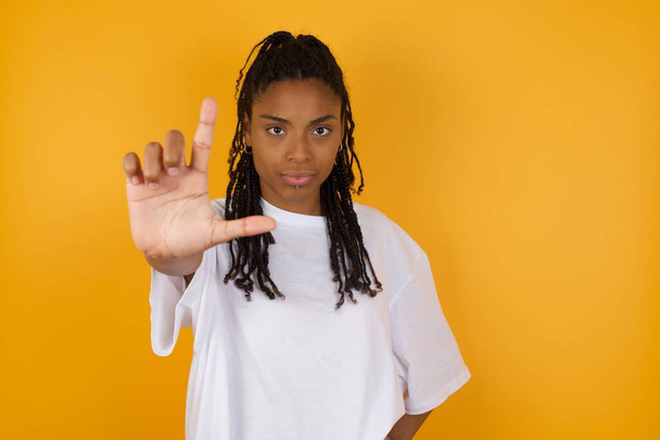 Afrikaans amerikaanse vrouw maakt verliezer gebaar op gele achtergrond - Foto, afbeelding