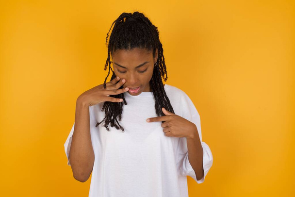 african american woman looking at t-shirt on yellow background - Фото, зображення