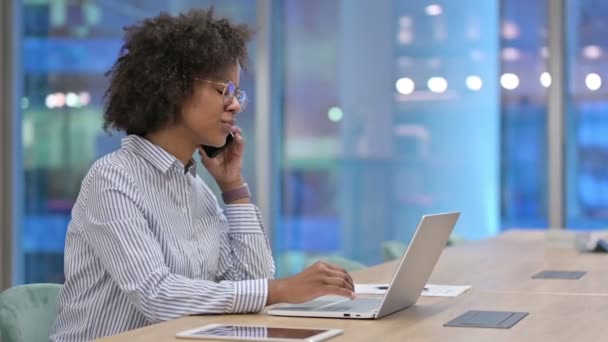 Empresária Africana com Laptop Talking no Smartphone no Escritório  - Filmagem, Vídeo