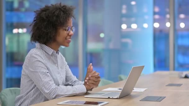 Heureuse femme d'affaires africaine faisant appel vidéo sur ordinateur portable au bureau  - Séquence, vidéo