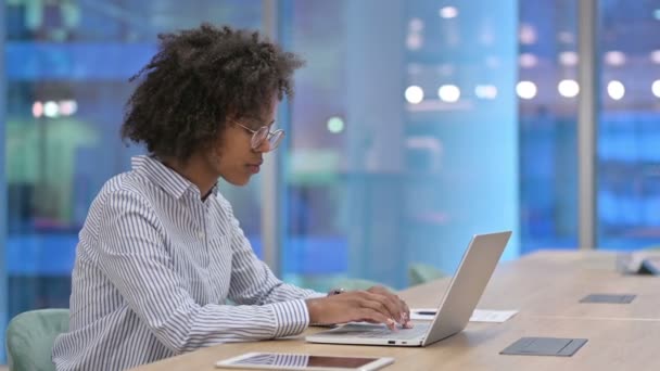 Εστιασμένη Αφρικανή επιχειρηματίας που εργάζεται σε φορητό υπολογιστή στο γραφείο  - Πλάνα, βίντεο