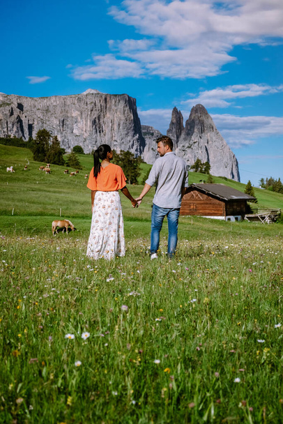 Пара чоловіків і жінок у відпустці в Доломітах Італії, Альп ді Сіузі - Сейзер Алм з групою Сассолунго - Лангкофель на задньому плані на заході сонця. Жовті весняні квіти і дерев'яні крейди в - Фото, зображення