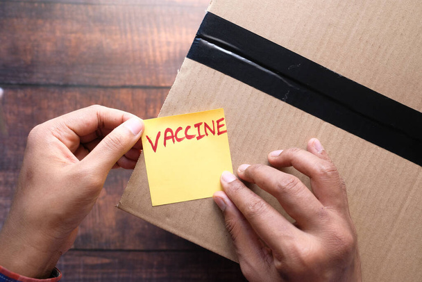Man holds the vaccine box on wooden background, - Photo, Image