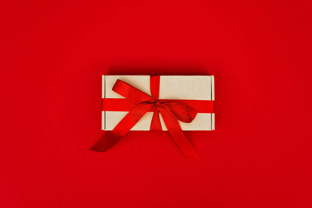 Ajándék doboz díszített szalag elszigetelt piros háttérrel. Karácsonyi és újévi koncepció. Fénymásolási hely. - Fotó, kép