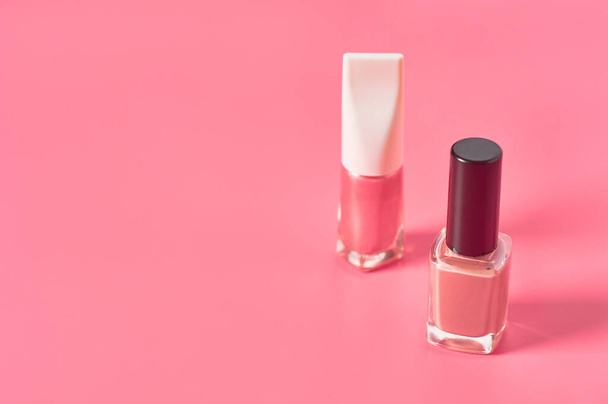 Two bottles of luxury nail polish on pink background. Beauty and fashion concept - Foto, Imagen