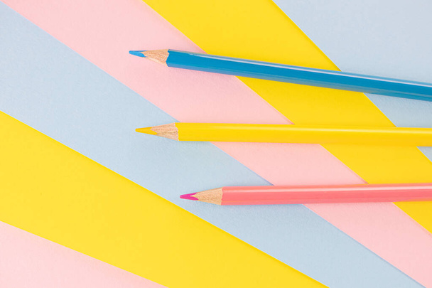 Zpátky do školy. Modré, růžové a žluté tužky leží na pozadí stejných barev. Tvůrčí minimalistický koncept dětské tvořivosti, kreslení. - Fotografie, Obrázek
