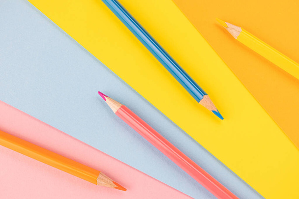 Zpátky do školy. Modré, růžové, oranžové a žluté tužky leží na stejném barevném pozadí. Tvůrčí minimalistický koncept dětské tvořivosti, kreslení. - Fotografie, Obrázek