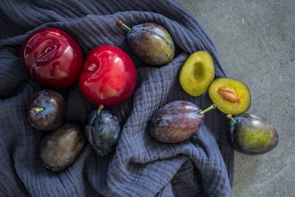 Świeże śliwki ogrodowe na granatowym tle teksturowanym. Widok z góry zdjęcie soczyste owoce.  - Zdjęcie, obraz