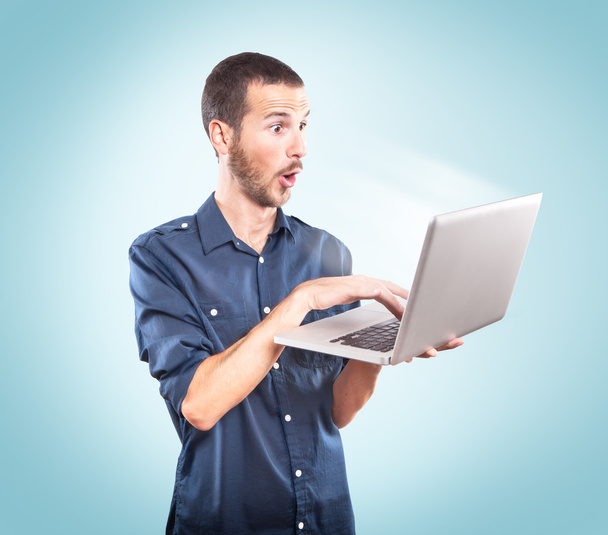 jonge man verrast met een laptop - Foto, afbeelding