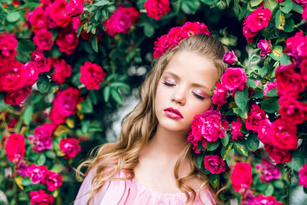girl in pink dress in a lush garden amid roses - Photo, Image