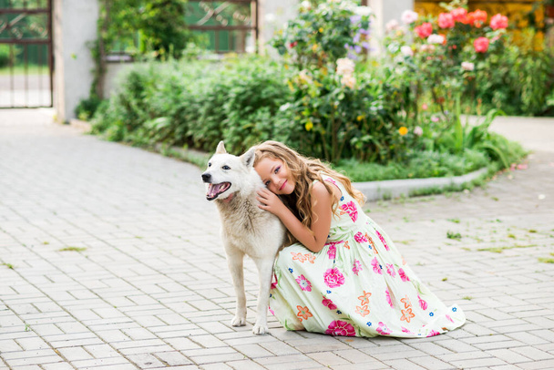 chica abraza al perro. Una chica joven en un hermoso vestido con un perro - Foto, Imagen