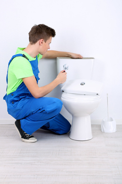 Plumber with toilet plunger on light background - Foto, imagen