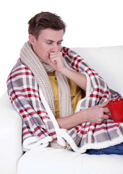 Guy wrapped in plaid lies on sofa on white background - Foto, afbeelding