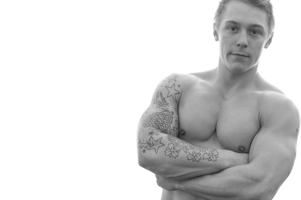νέοι bodybuilder που στέκεται με τα χέρια σταυρωμένα, απομονώνονται σε λευκό φόντο - Φωτογραφία, εικόνα