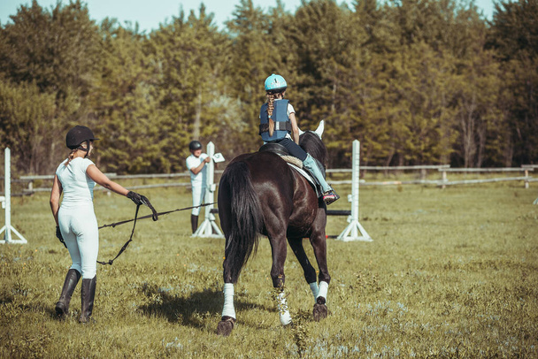 Una niña está aprendiendo a montar a caballo.. - Foto, Imagen