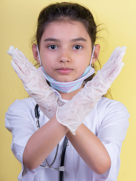 Een grappig meisje met een stethoscoop in doktersuniform. Opwinding en fascinatie concept. Coronavirus achtergrond. dwaze grimmige komische gekke gebaar. Grappige uitdrukking. Covidius 19 - Foto, afbeelding