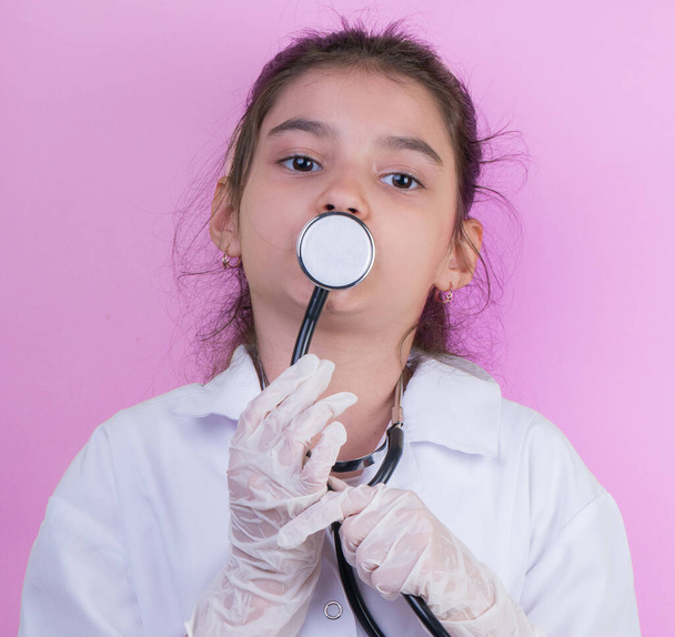 Asia Ärztin mit Stethoskop während sie Doktoruniform trägt. Stehen isoliert über farbigem Hintergrund. covid-19. Quarantäne. Mädchen spielt Ärztin. Ausbildungs- und Berufskonzept - Foto, Bild