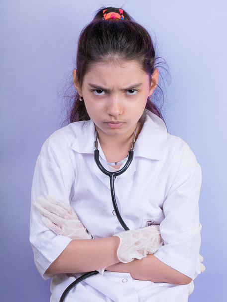 Little funny girl with a collorful stethoscope while wearing Doctor's uniform. Excitement and fascination concept. Coronavirus background. foolish grimaces comical crazy gestur.  Funny expression. covid 19 - Photo, Image