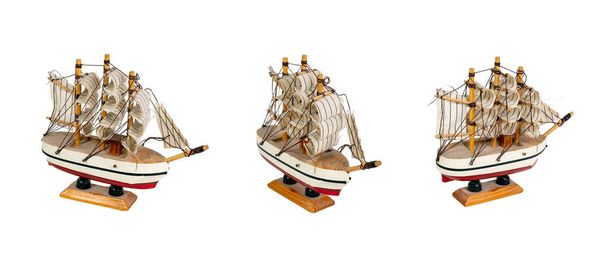 Set von Spielzeugboot-Segelboot auf einem Holzständer isoliert auf weißem Hintergrund. Schiffsmodell mit rotem Streifen. - Foto, Bild
