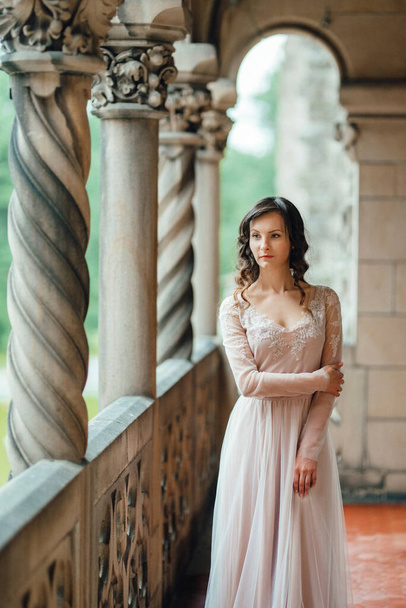Дівчина в рожевій сукні на тлі середньовічного польського кам'яного замку. - Фото, зображення