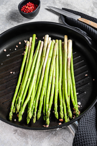 Cooking green asparagus in a frying pan. Black background. Top view. - Photo, Image