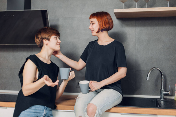 two sisters are talking in the kitchen while drinking tea - Fotoğraf, Görsel