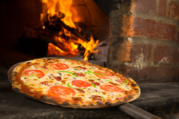 Pizza entering a wood oven - Photo, Image