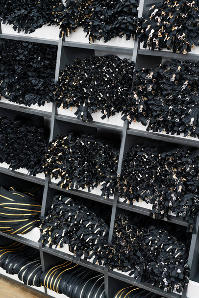 Regale mit Reißverschlüssen für Schuhe und Kleidersäcke in den Regalen einer industriellen Schuhfabrik. Modernes Lager im Betrieb - Foto, Bild