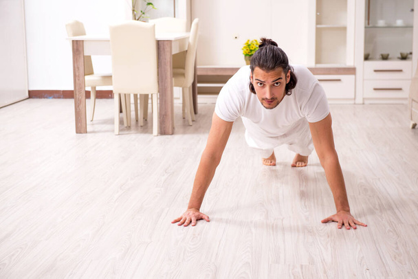 Young man doing physical exercises at home - Photo, Image
