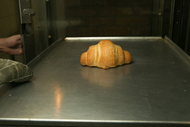 Proceso de fabricación de cruasanes. El croissant se cuece en el horno hasta que esté tierno. El chef saca el producto terminado. - Foto, imagen
