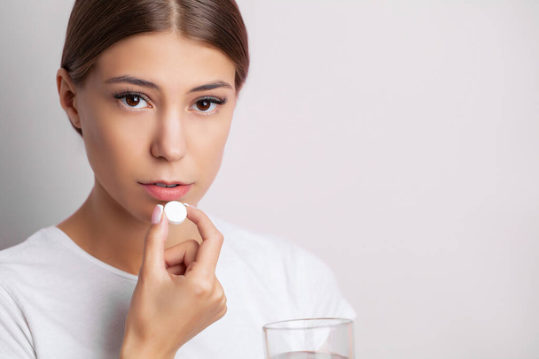 Junge Frau nimmt Tablette gegen Kopfschmerzen - Foto, Bild