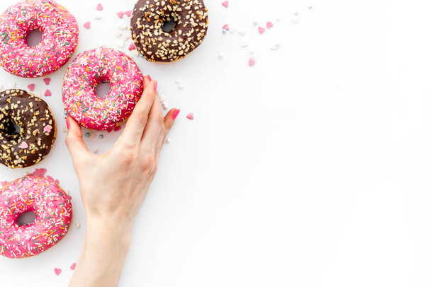 Hand holding glazed donut swith sprinkles, above view - Fotografie, Obrázek