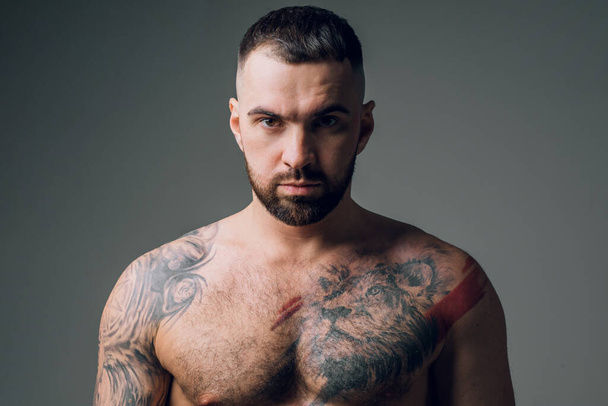 handsome awesome bearded man with tattoo is looking at the camera - Fotografie, Obrázek