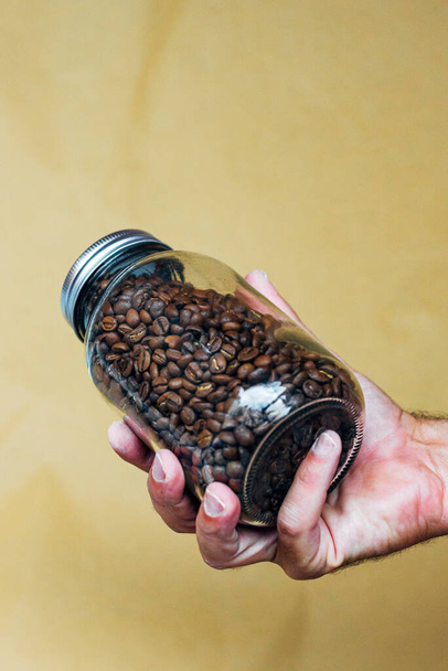 Hand mit Glaskanne voller Kaffeebohnen - Foto, Bild