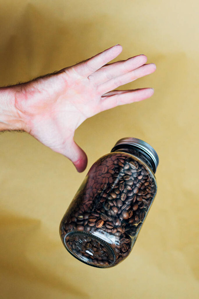 Mano con maceta de vidrio llena de granos de café - Foto, imagen