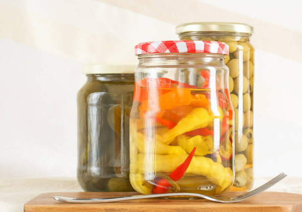 Tři skleněné sklenice s konzervovanými paprikami, olivami, okurkami a vidličkou - Fotografie, Obrázek