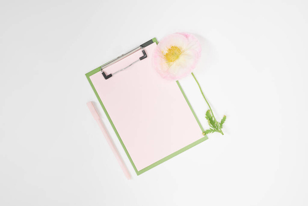 Papel em branco na área de transferência verde com caneta e flor
 - Foto, Imagem