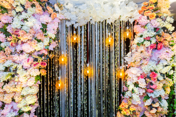 結婚式のステージの装飾にぶら下がっ装飾アンティークエジソンスタイルフィラメント電球とカラフルな人工花. - 写真・画像