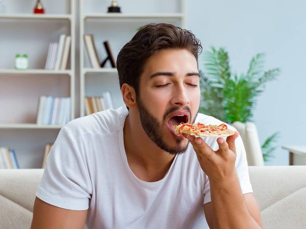 Hombre comiendo pizza teniendo una comida para llevar en casa descansando relajado - Foto, Imagen