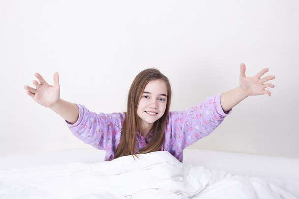 χαμογελαστό κορίτσι στο κρεβάτι ξυπνάτε και χαιρετισμό - Φωτογραφία, εικόνα